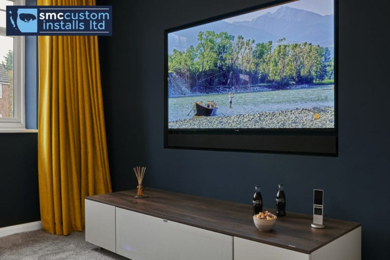 Wall-mounted TV above walnut media unit on navy wall with mustard curtain, snug
