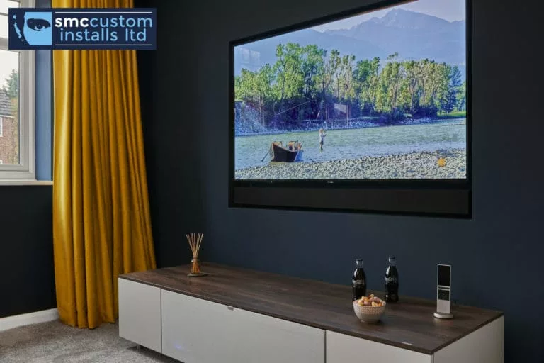 Wall-mounted TV above walnut media unit on navy wall with mustard curtain, snug
