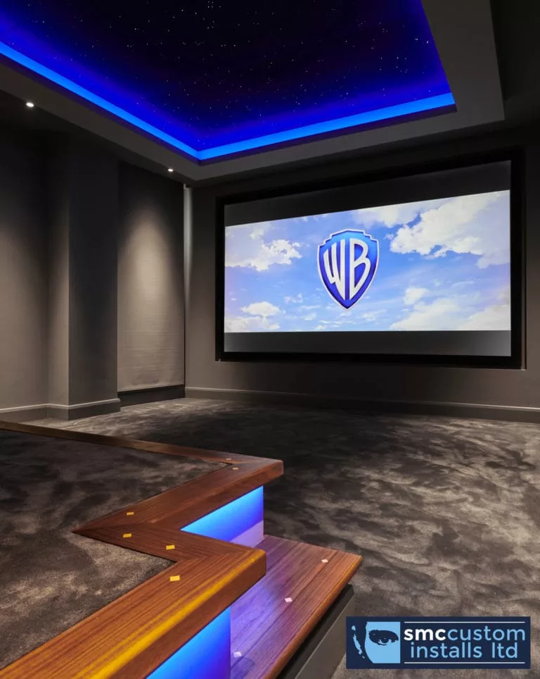 Star ceiling with blue LED cove above projection screen and walnut-trimmed seating tier