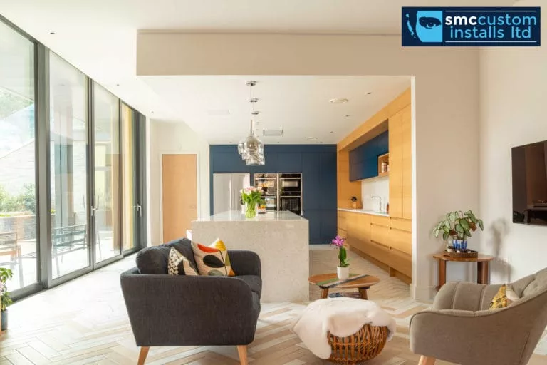 Open-plan kitchen and living space with wall-mounted TV and floor-to-ceiling glazing