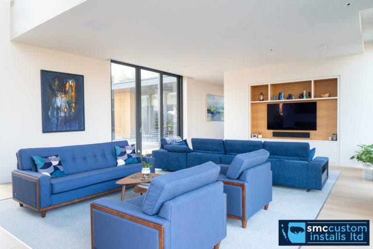 Living room with blue sofas and wall-mounted TV recessed into bespoke media joinery