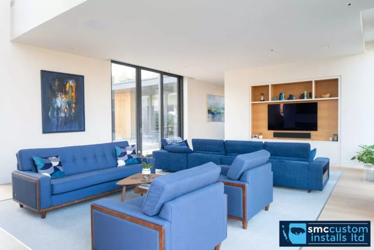 Living room with blue sofas and wall-mounted TV recessed into bespoke media joinery