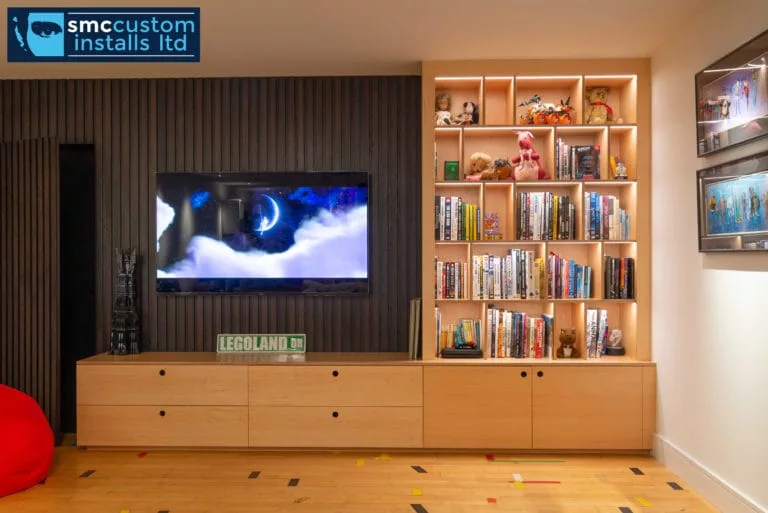 Wall-mounted TV in bespoke oak media wall with backlit shelving, family living room