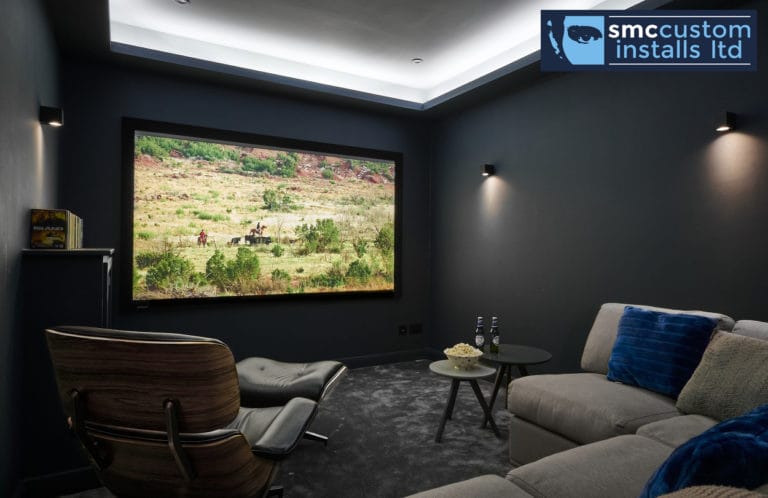 Dedicated home cinema room with projection screen, chaise longue and cove ceiling lighting