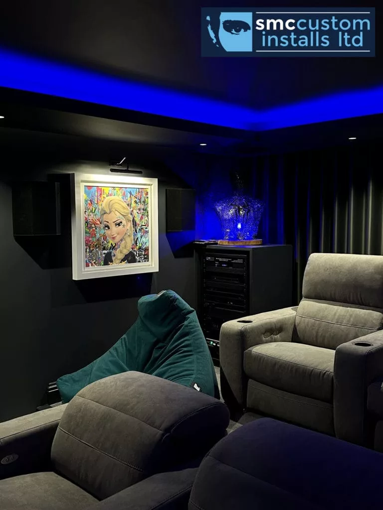 Home cinema corner with wall-mounted surround speakers, picture-lit artwork and recliner seating