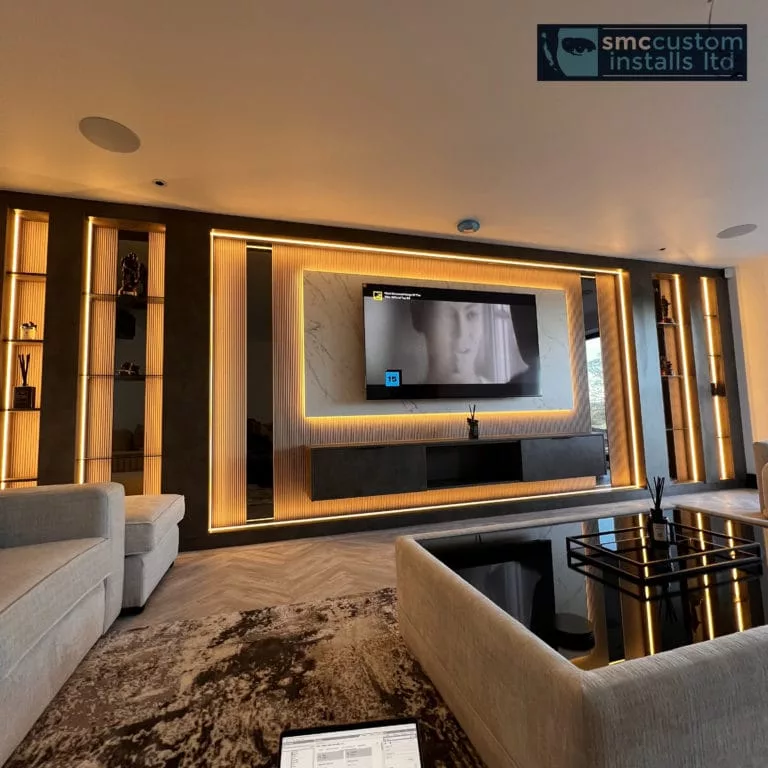 Living room media wall with backlit panelling, wall-mounted TV and in-ceiling speakers