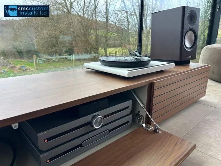Turntable and loudspeaker on walnut media cabinet with amplifier concealed in drawer below