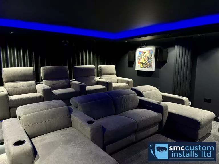 Grey cinema recliners with cup holders under blue LED coving and dark acoustic drapes