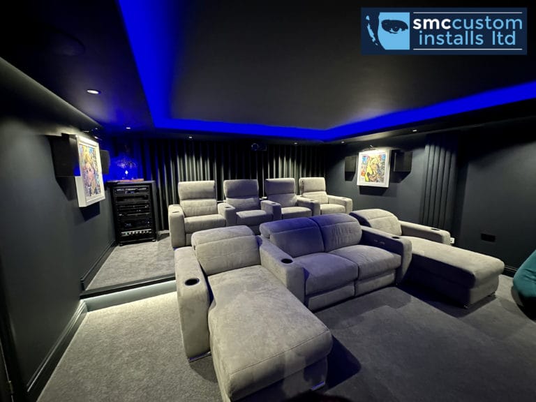 Two rows of recliner seating in a dedicated home cinema with blue LED ceiling