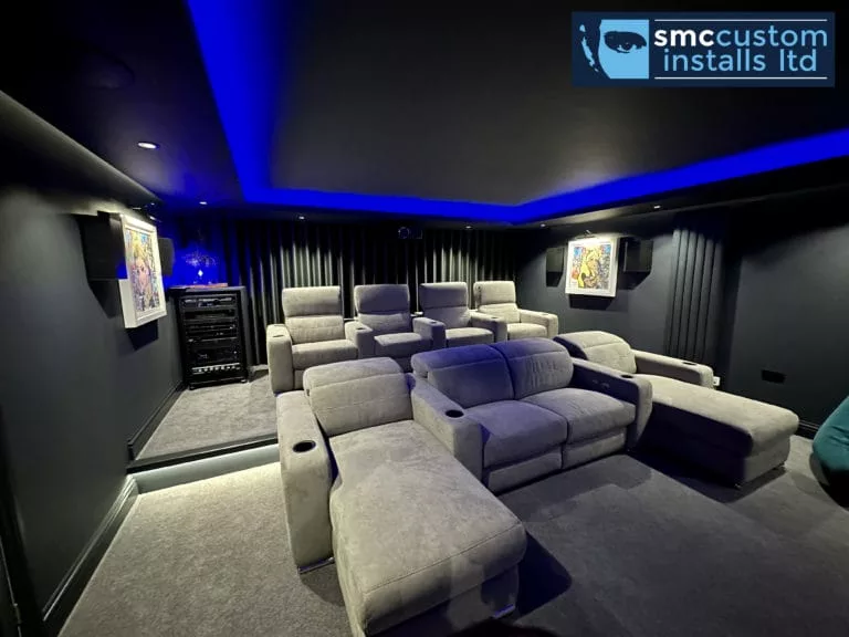 Two rows of recliner seating in a dedicated home cinema with blue LED ceiling
