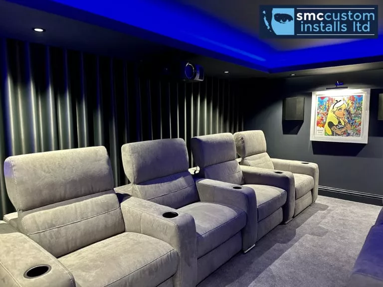 Row of grey recliner cinema seats beneath blue LED coving in dedicated cinema room