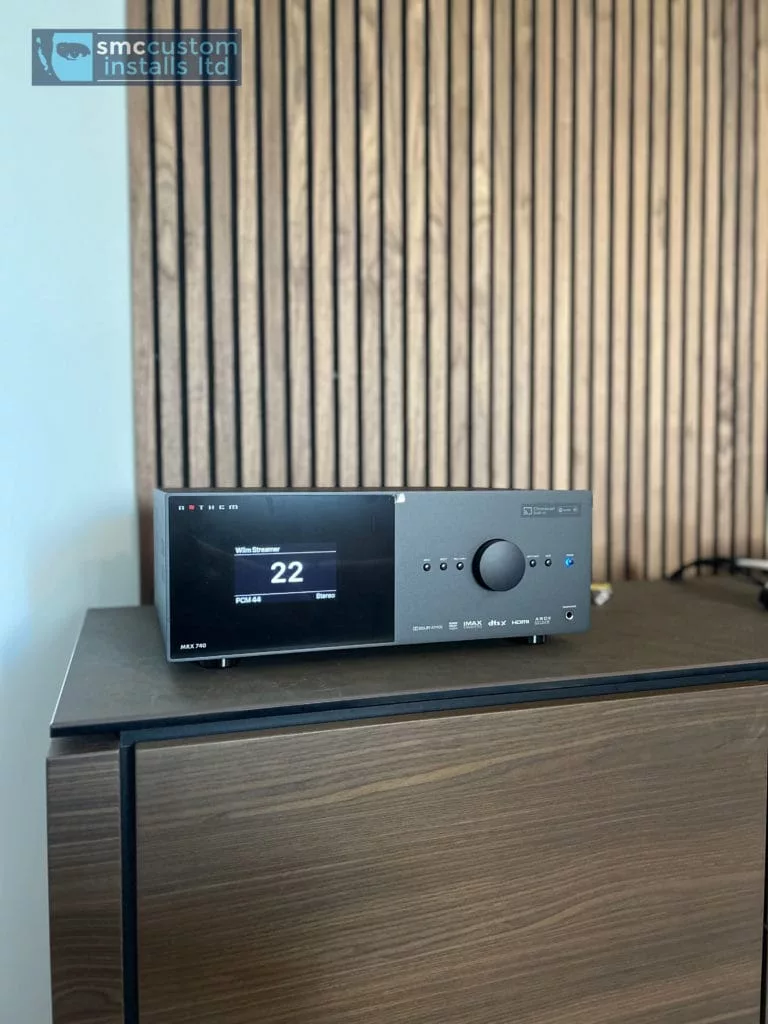 Anthem home cinema processor on a cabinet against a slatted wood panel wall