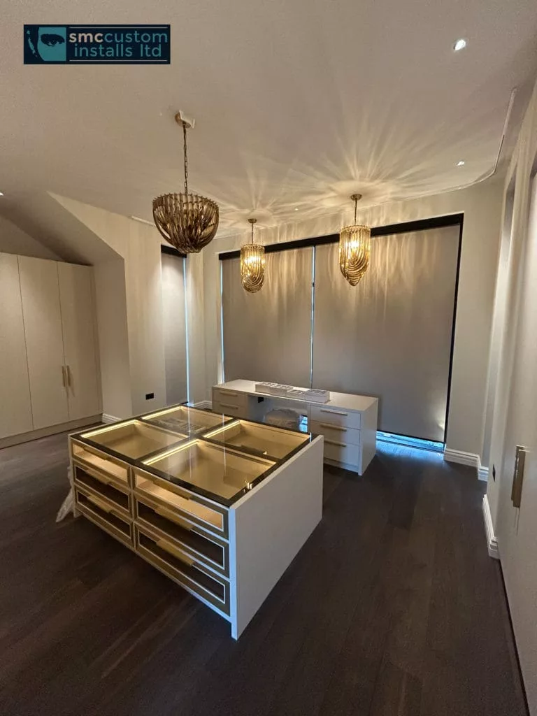 Dressing room with glass-topped island, pendant lights and roller blinds lowered