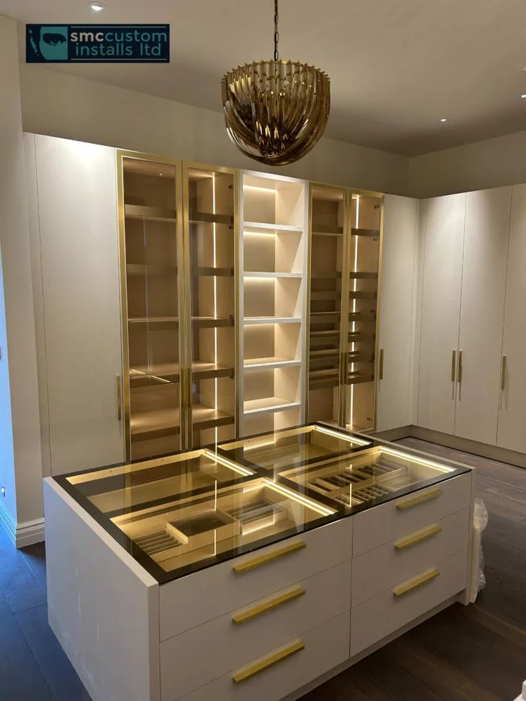 Dressing room with illuminated brass-framed display cabinets and lit glass-topped island