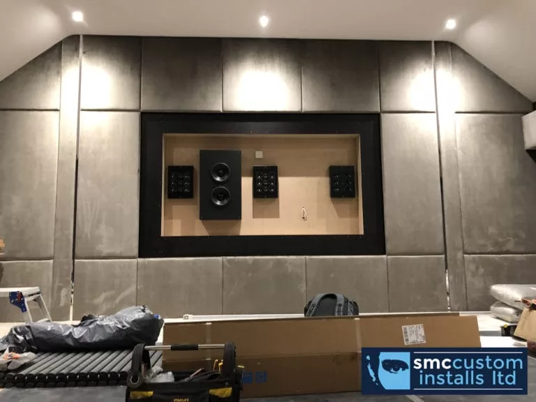 Fabric acoustic wall panels fitted around a media wall recess during cinema installation