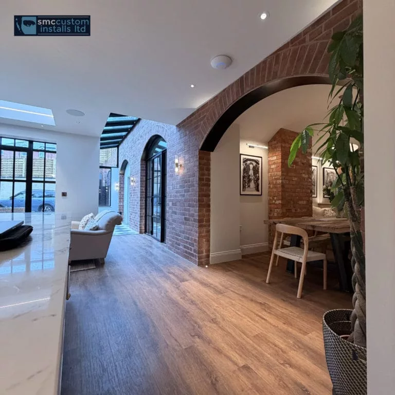 Hallway with exposed brick archways, wall lights and an in-ceiling speaker