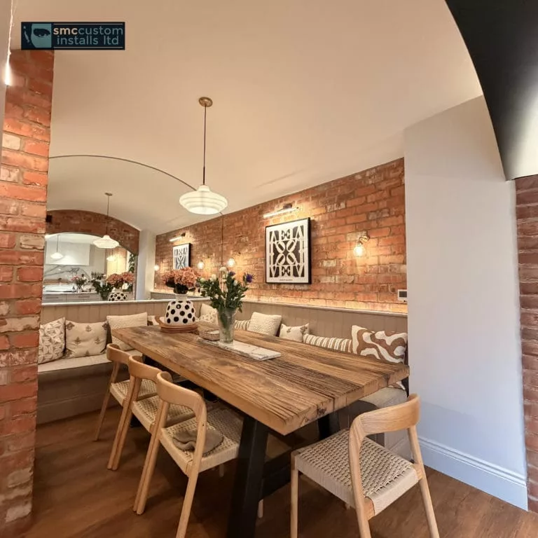 Exposed-brick dining room with bench seating, wall lights and pendant over rustic table