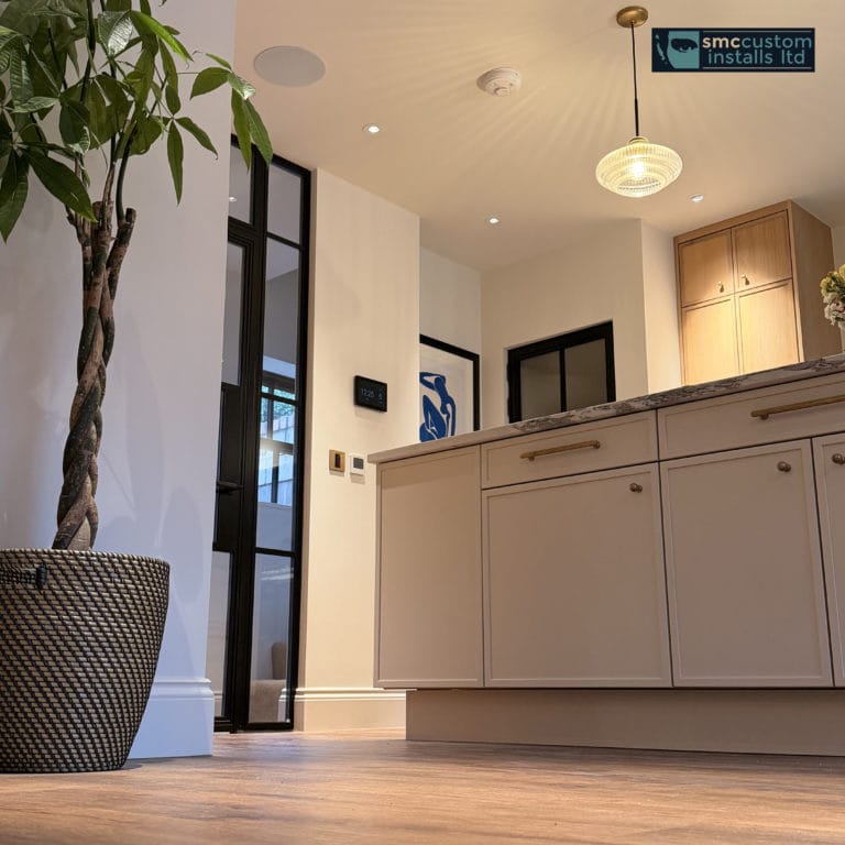 Kitchen island with pendant light, in-ceiling speaker and wall keypads by glazed door