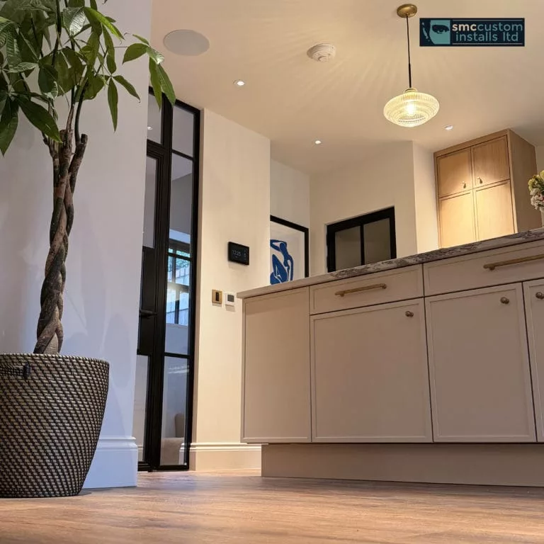 Kitchen island with pendant light, in-ceiling speaker and wall keypads by glazed door