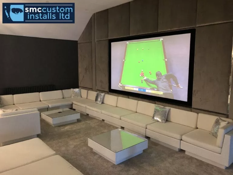 Media room with large projection screen, fabric-panelled walls and modular sofa seating
