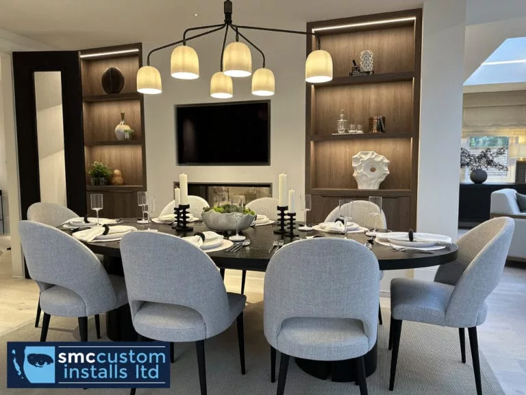 Dining room with wall-mounted TV recessed into dark joinery and lit display shelving