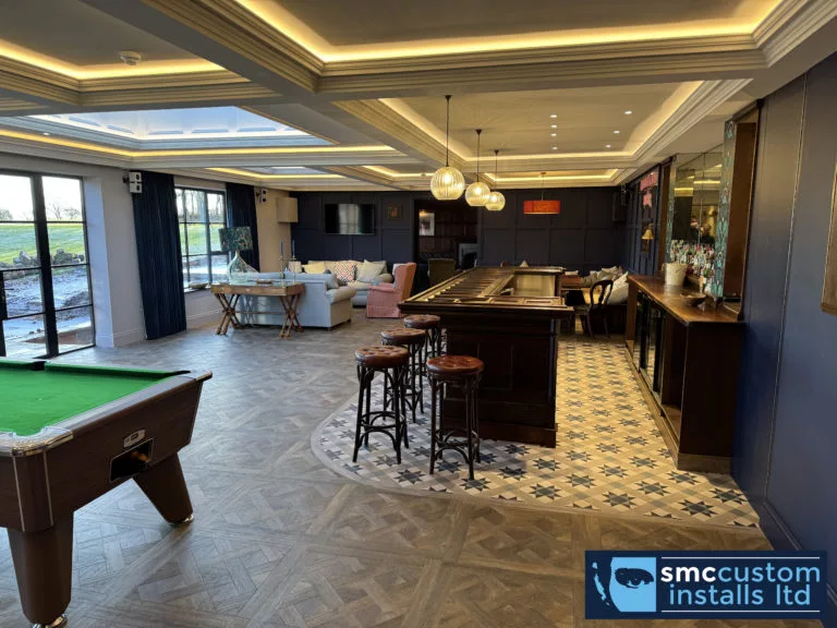 Wide view of the games room with pool table, home bar and lounge seating