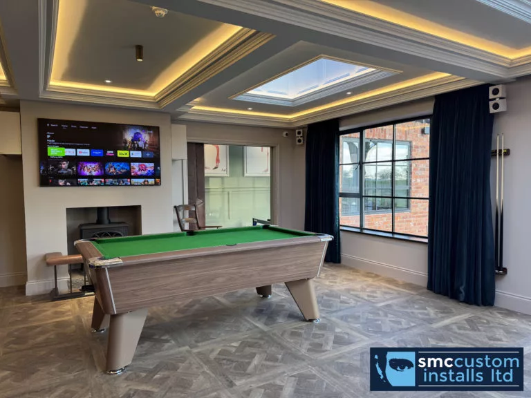 Two wall-mounted TVs above the pool table in a games room with roof lantern