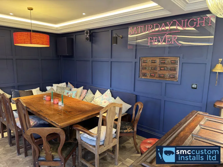 Banquette dining seating in the home bar with wall-mounted speakers and cove lighting