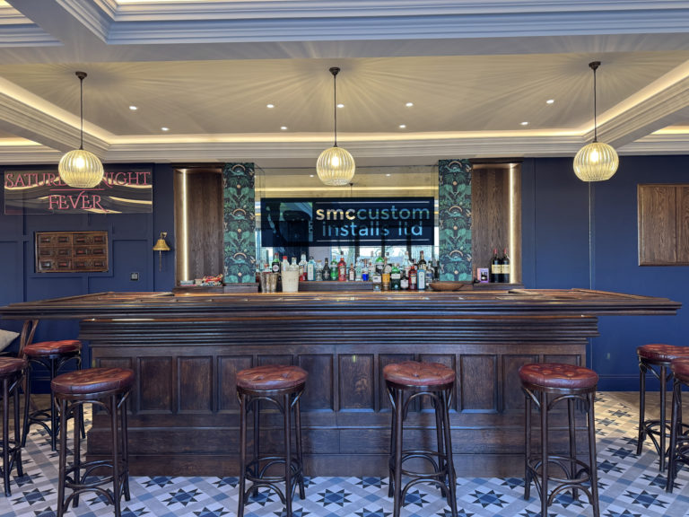 Bespoke home bar with stools, pendant lights and a TV mounted behind the counter