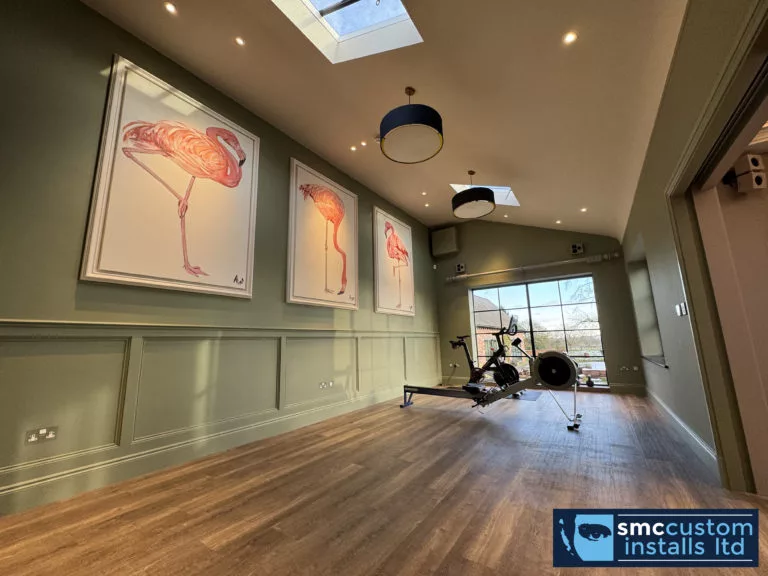 Green-panelled home gym with skylights, rowing machine and exercise bike