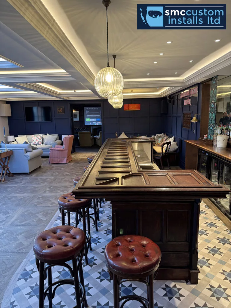 Shuffleboard table with leather stools in a bar lounge, wall-mounted TVs beyond