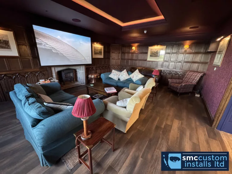 Projection screen in an oak-panelled lounge cinema with coffered ceiling and concealed LED lighting