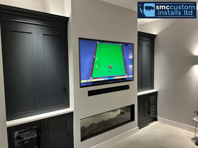 Media wall with recessed TV, soundbar niche and inset fire between dark cabinetry