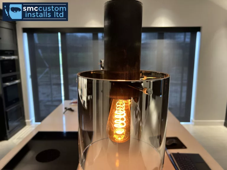 Smoked-glass pendant light with filament bulb hanging over a kitchen island