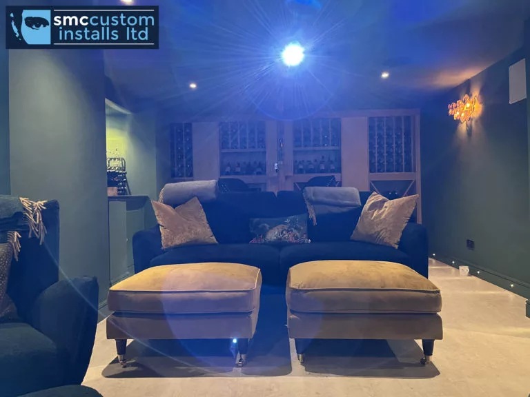 Cinema room seating with deep sofa and footstools under dimmed lighting