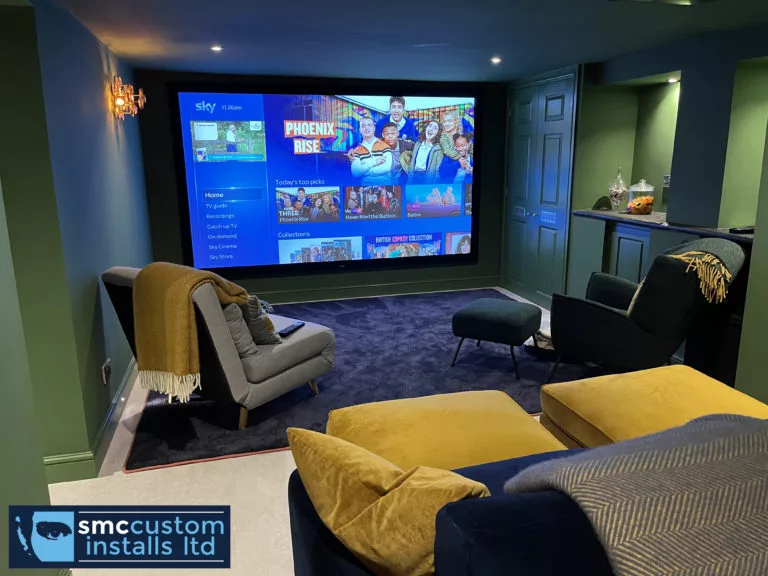 Home cinema room with large projection screen, teal walls and mustard and navy seating