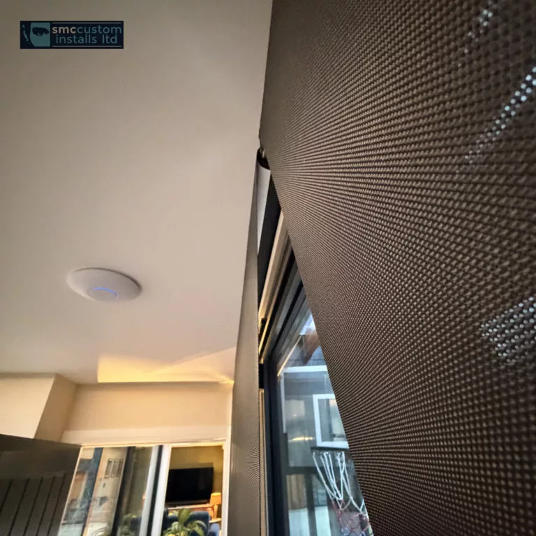In-ceiling speaker and textured acoustic wall panelling beside a window reveal