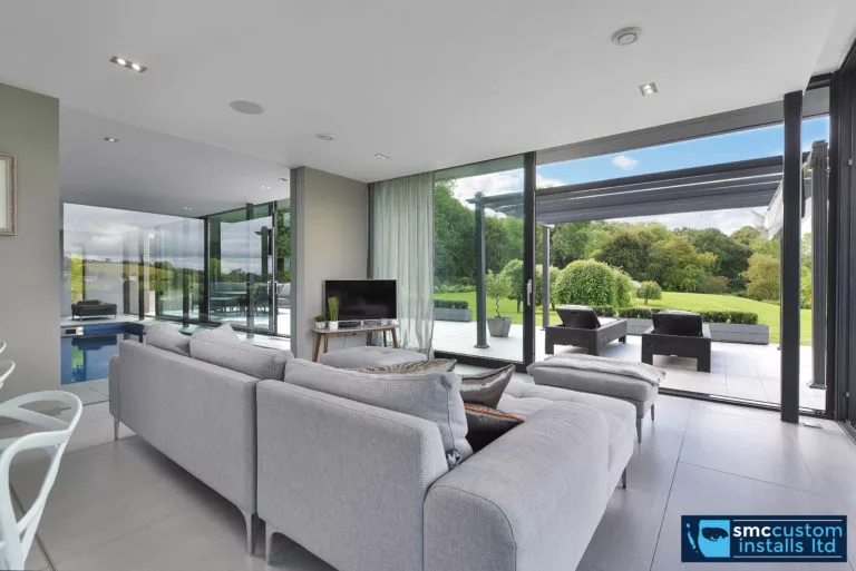 Grey open-plan living room with recessed downlights and sliding doors to a terrace