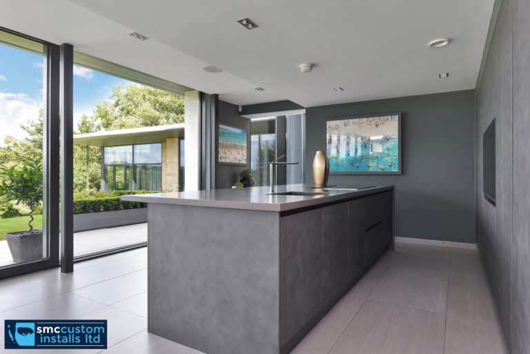 Contemporary kitchen island with concrete finish beside sliding glass doors to the garden