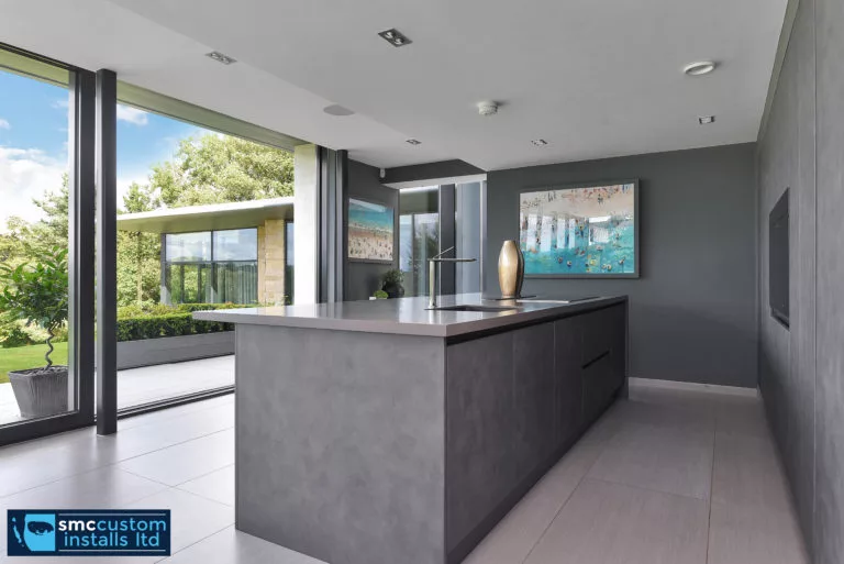 Contemporary kitchen island with concrete finish beside sliding glass doors to the garden